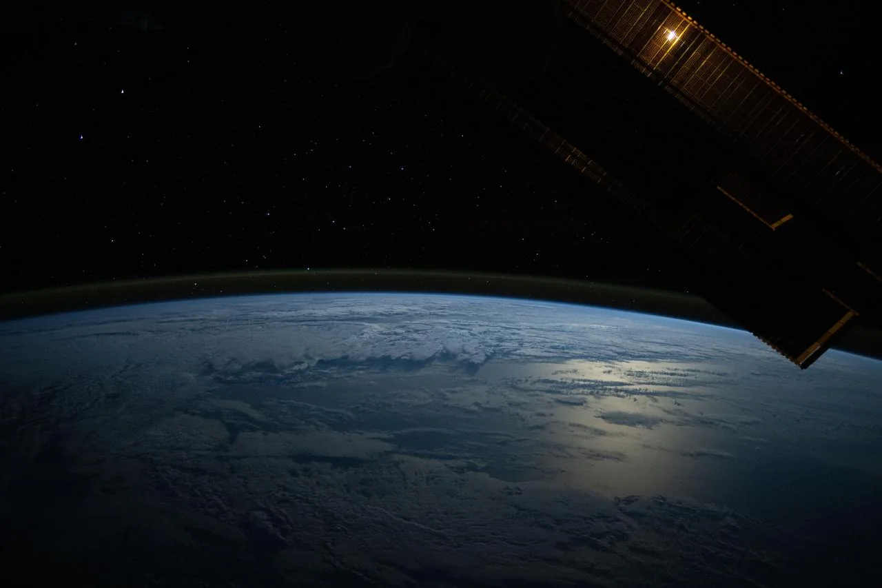 Mondlicht spiegelt sich im Pazifik unter dem leuchtenden Rand der Atmosphäre